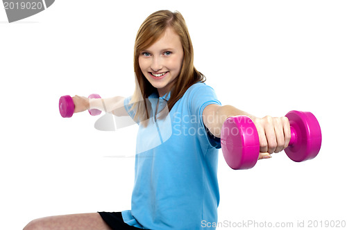 Image of Cute young girl stretching dumbbells sideways