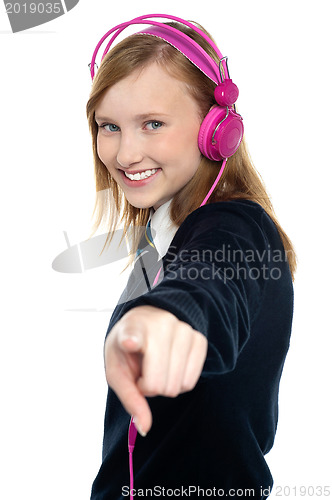 Image of Pretty musical girl enjoying music and pointing at you