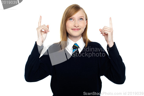 Image of Amused schoolgirl looking and pointing upwards