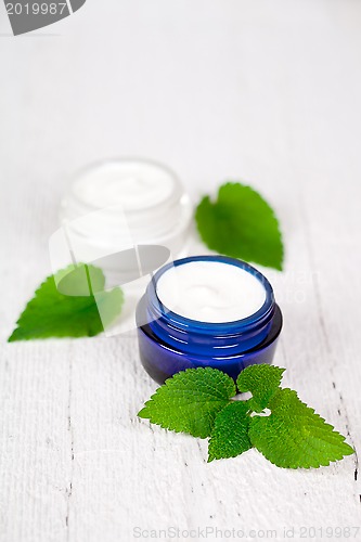 Image of face cream in jars with urtica leaves