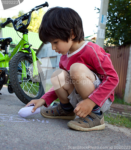 Image of boy  drawing with chalk on asphalt