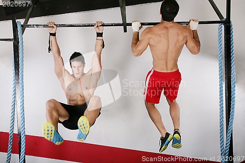 Image of athletic group executing exercise tightening on horizontal bar. 