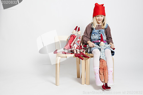 Image of Happy young girl playing with toy Christmas elf dolls