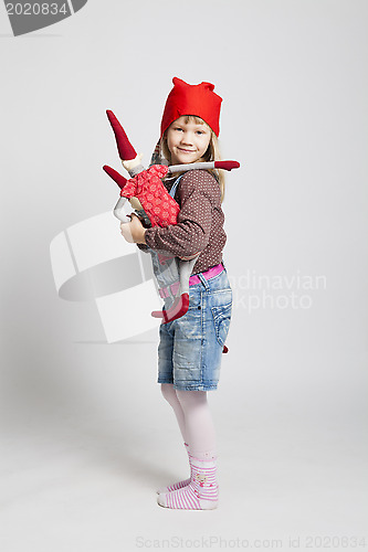 Image of Happy young girl holding toy Christmas elf doll