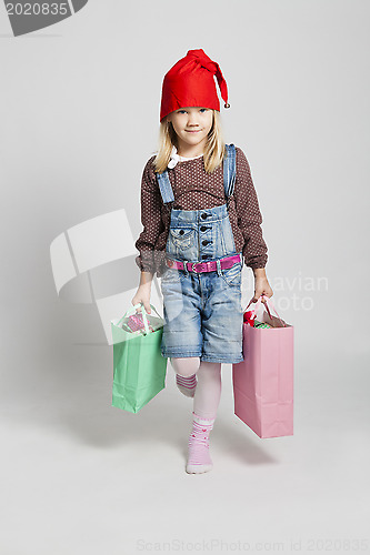 Image of Happy young girl carrying Christmas shopping bags