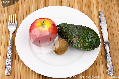 Image of kiwi, avocado and apple on a plate with cutlery