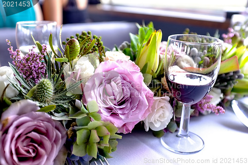 Image of Glass of wine placed beside freshly arranged flowers