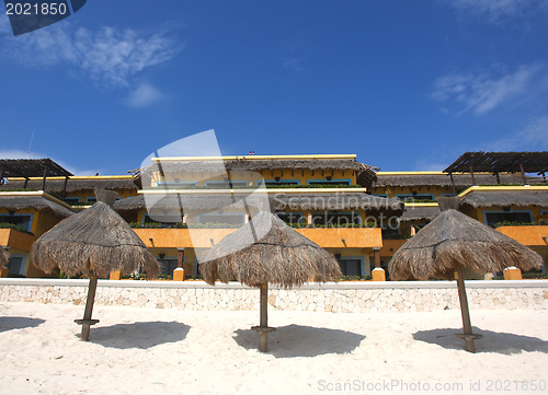 Image of Three grass umbrellas on a resort beach 