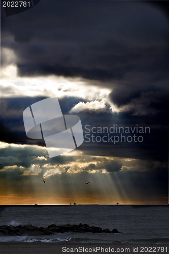 Image of Sunbeams emanating through clouds above the ocean 