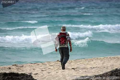 Image of Man walking on the beach in the morning.