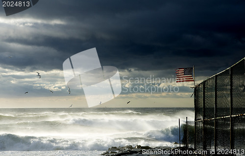 Image of American flag on a fence along the beach  