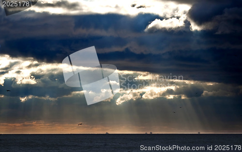 Image of Sunbeams emanating through clouds above the ocean 