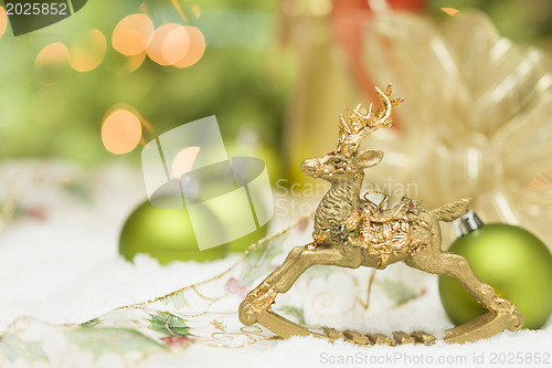 Image of Golden Christmas Reindeer Ornament Among Snow, Bulbs and Ribbon