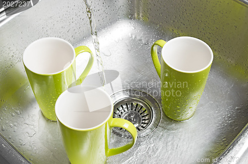 Image of Washing green cups in the kitchen sink