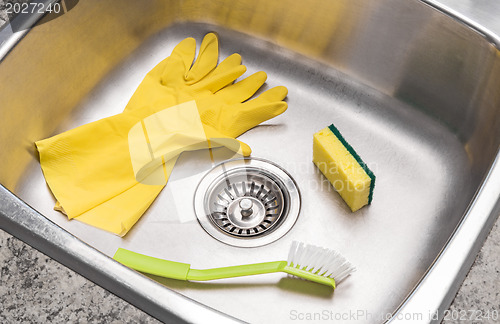 Image of Gloves, sponge and brush in a clean kitchen sink