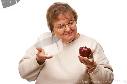 Image of Confused Senior Woman Holding Apple and Vitamins