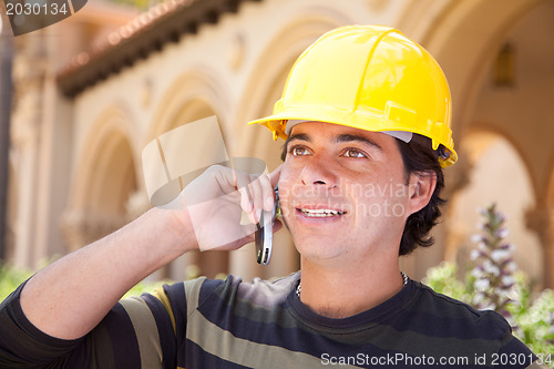 Image of Handsome Hispanic Contractor on Phone with Hard Hat Outside