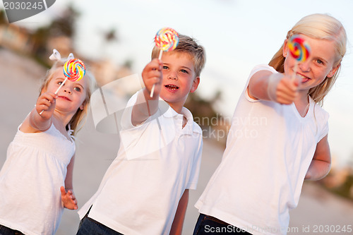 Image of Cute Brother and Sisters Enjoying Their Lollipops Outside