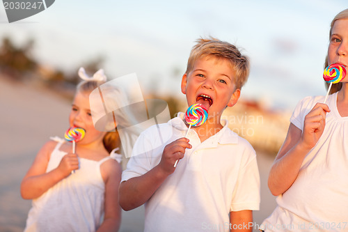 Image of Cute Brother and Sisters Enjoying Their Lollipops Outside