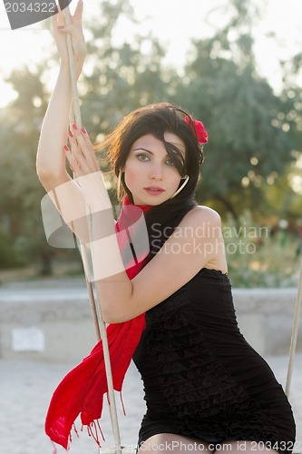 Image of sensual young woman sitting on a swing