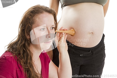 Image of young midwife listening at pregnant human belly