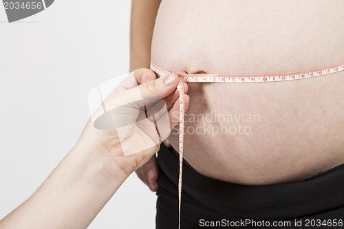 Image of hand of midwife measuring pregnant belly