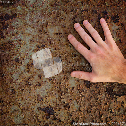 Image of Hand on old rusty metal surface