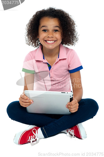 Image of Cool girl kid sitting on the floor holding tablet pc