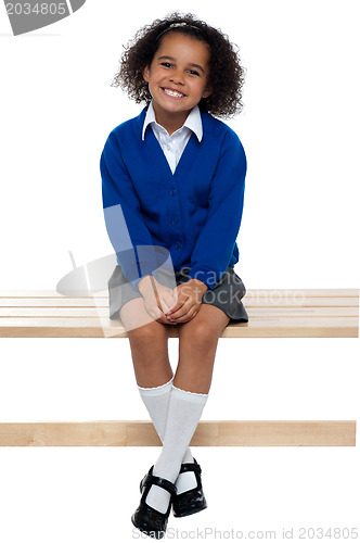 Image of Pretty school girl seated comfortably on a bench