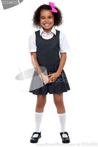 Image of Cheerful young kid in pinafore dress posing smilingly