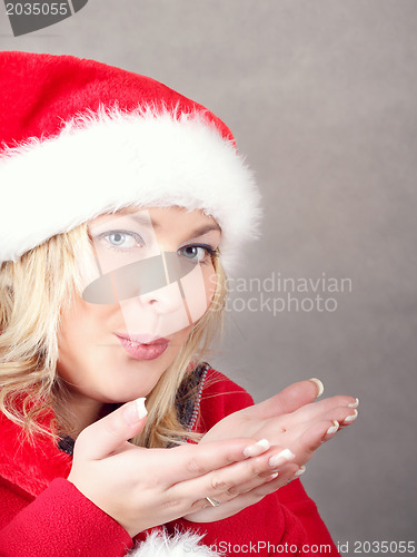 Image of Portrait of joyful pretty woman blowing in red santa claus hat 