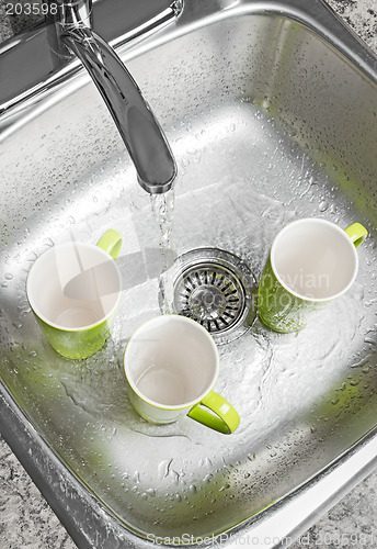 Image of Washing cups in the kitchen sink