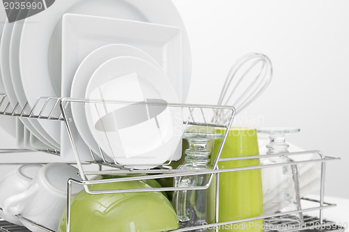 Image of Green and white dishes drying on dish rack