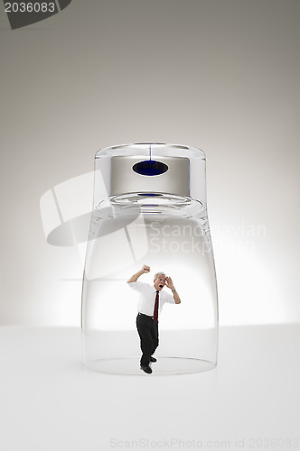 Image of Senior businessman trapped under a glass