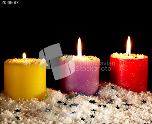 Image of Three candles with artificial snow.