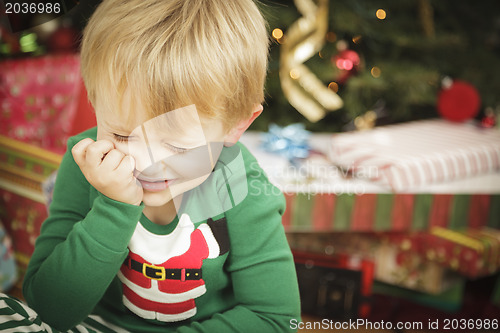 Image of Young Grumpy Boy Sitting Near Christmas Tree