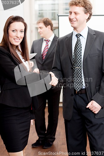 Image of business woman and man shake hands in office