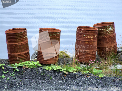 Image of Old rusty waste barrels by the sea