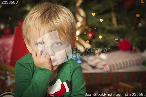 Image of Young Grumpy Boy Sitting Near Christmas Tree