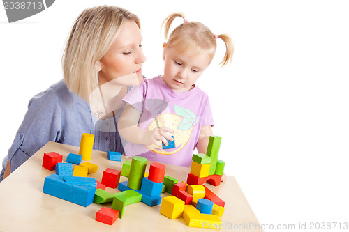 Image of little girl and her mother playing with toy blocks