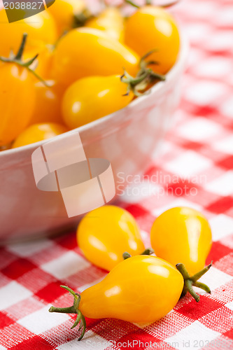 Image of yellow tomatoes on picnic tablecloth