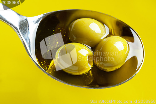 Image of green olives in spoon with olive oil