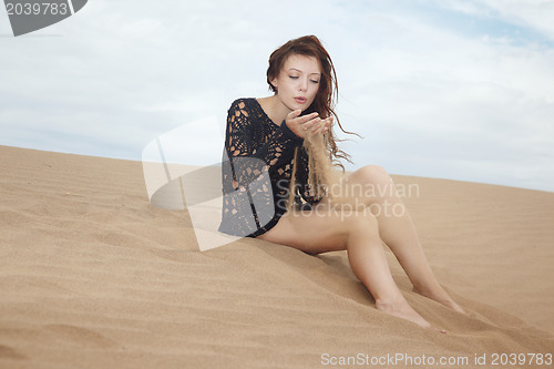 Image of Lady blowing on sand grains