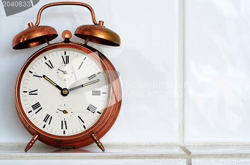 Image of vintage copper alarm clock on the mantelshelf 