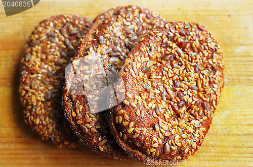 Image of three sandwich buns with sesame seeds on cutting board 