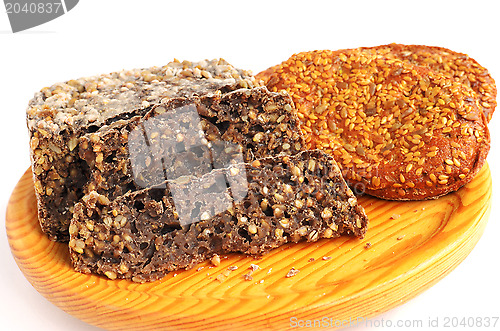 Image of homemade brown bread and buns with sesame seeds on cutting board