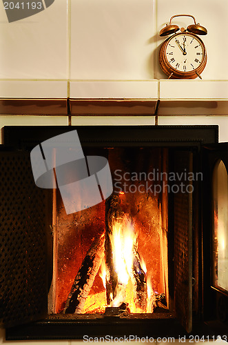 Image of fireplace and  old-fashioned copper alarm clock on the mantelshe