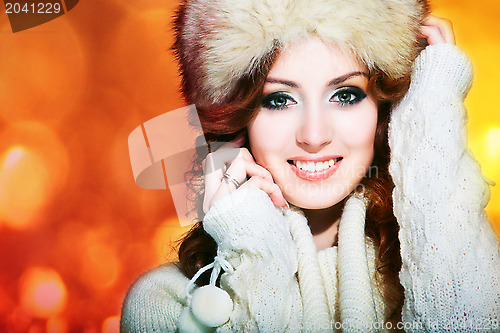 Image of beautiful girl with winter fur cap on bright background