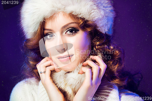 Image of beautiful girl with winter fur cap on purple 