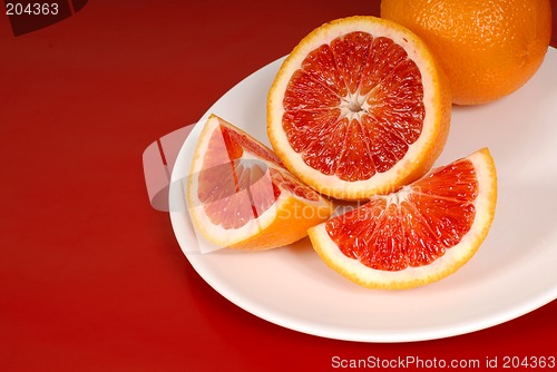 Image of Whole and cut up blood oranges on white plate
